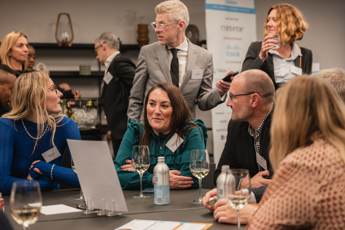 An informal group of delegates seated and standing round a table.