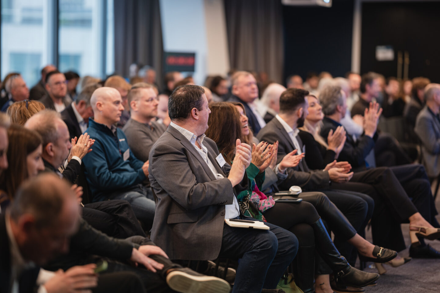 Seated conference delegates clapping.